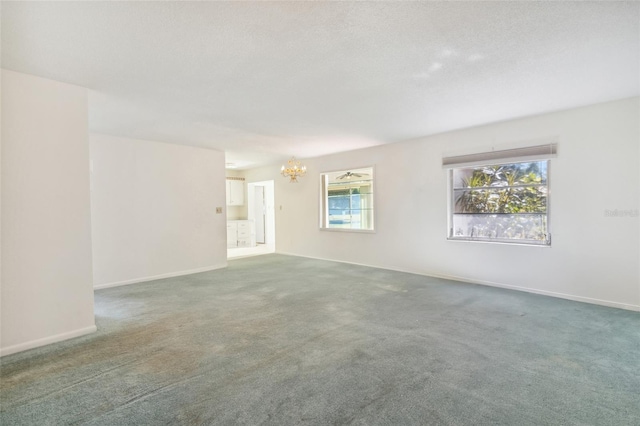 carpeted spare room with a chandelier