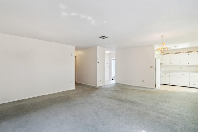 spare room with light colored carpet and an inviting chandelier