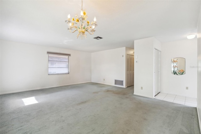 carpeted spare room featuring a chandelier