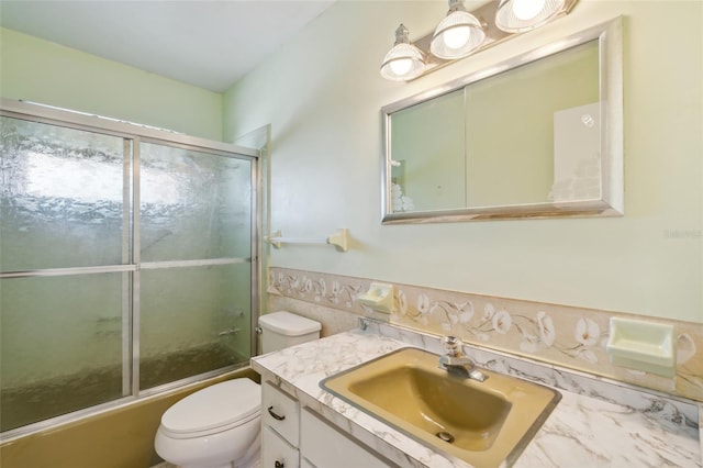 full bathroom featuring toilet, combined bath / shower with glass door, and vanity