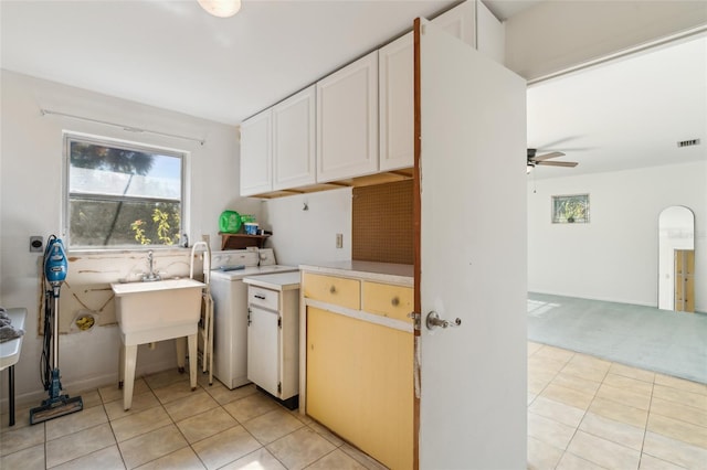 laundry room with ceiling fan, light tile patterned floors, cabinets, and washer / dryer