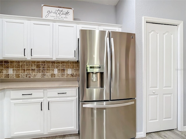 kitchen featuring white cabinetry, light countertops, stainless steel refrigerator with ice dispenser, and backsplash