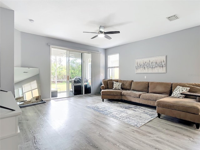 living area with ceiling fan, visible vents, and wood finished floors