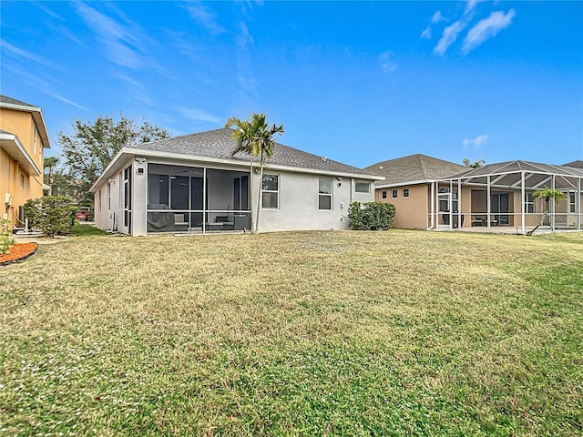 rear view of house with stucco siding, a lawn, and glass enclosure