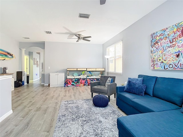 living area with a ceiling fan, visible vents, ornate columns, baseboards, and light wood-style flooring