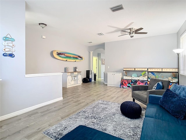 living room featuring arched walkways, visible vents, ornate columns, and wood finished floors