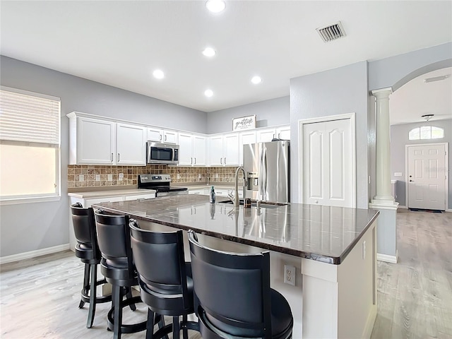 kitchen with visible vents, decorative columns, arched walkways, appliances with stainless steel finishes, and decorative backsplash