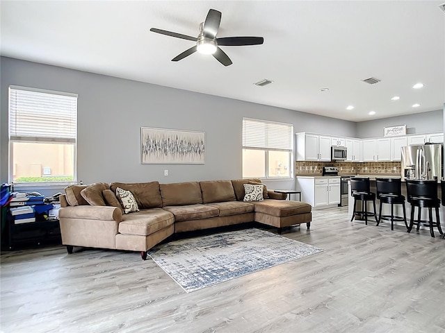 living room featuring light wood-type flooring, visible vents, and plenty of natural light