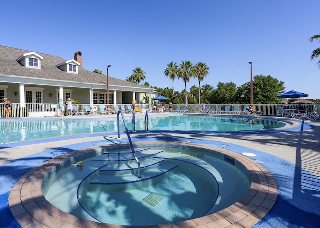 community pool featuring a patio area, a community hot tub, and fence