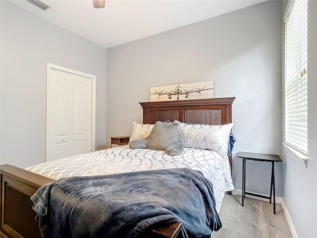 bedroom featuring a ceiling fan, baseboards, visible vents, light wood-style flooring, and a closet