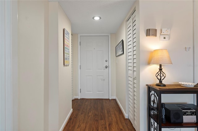 hallway with a textured ceiling and dark hardwood / wood-style floors