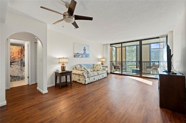 living room featuring a textured ceiling, ceiling fan, expansive windows, and dark hardwood / wood-style floors