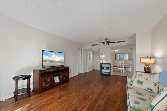 living room featuring ceiling fan, dark hardwood / wood-style flooring, and a textured ceiling