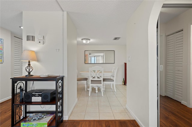 hallway with light hardwood / wood-style floors and a textured ceiling