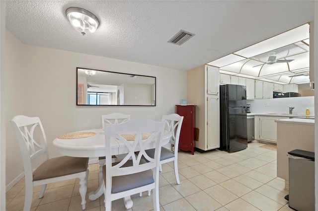 tiled dining room with ceiling fan, sink, and a textured ceiling