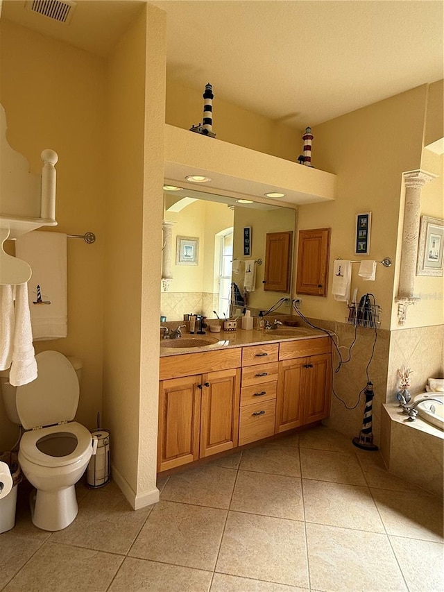 bathroom with tile patterned flooring, vanity, toilet, and tiled tub