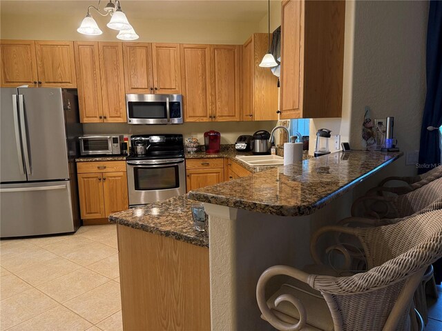 kitchen with dark stone countertops, sink, hanging light fixtures, and appliances with stainless steel finishes