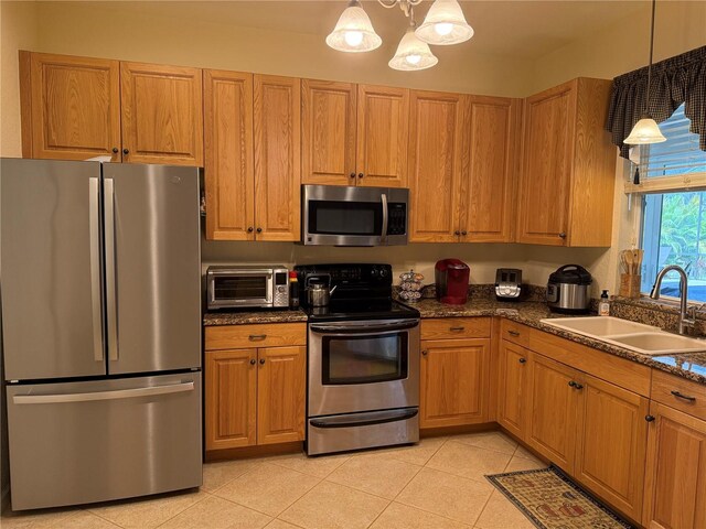 kitchen featuring appliances with stainless steel finishes, a notable chandelier, pendant lighting, and sink