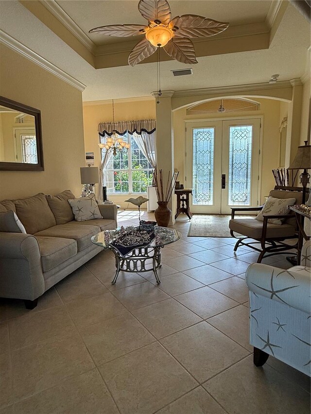 living room with ceiling fan, french doors, crown molding, a tray ceiling, and light tile patterned floors