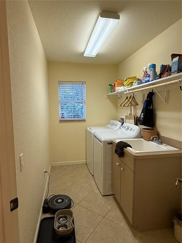 washroom with cabinets, separate washer and dryer, a textured ceiling, and light tile patterned floors