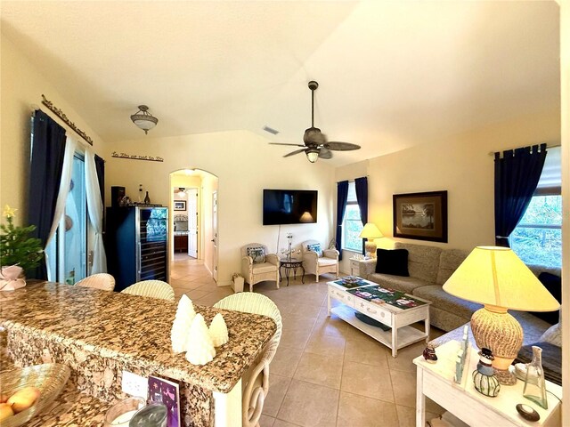 living room with vaulted ceiling, ceiling fan, and light tile patterned flooring