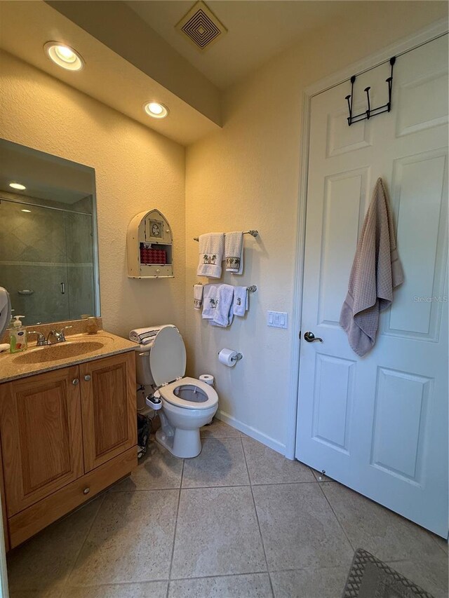 bathroom featuring tile patterned flooring, vanity, toilet, and an enclosed shower