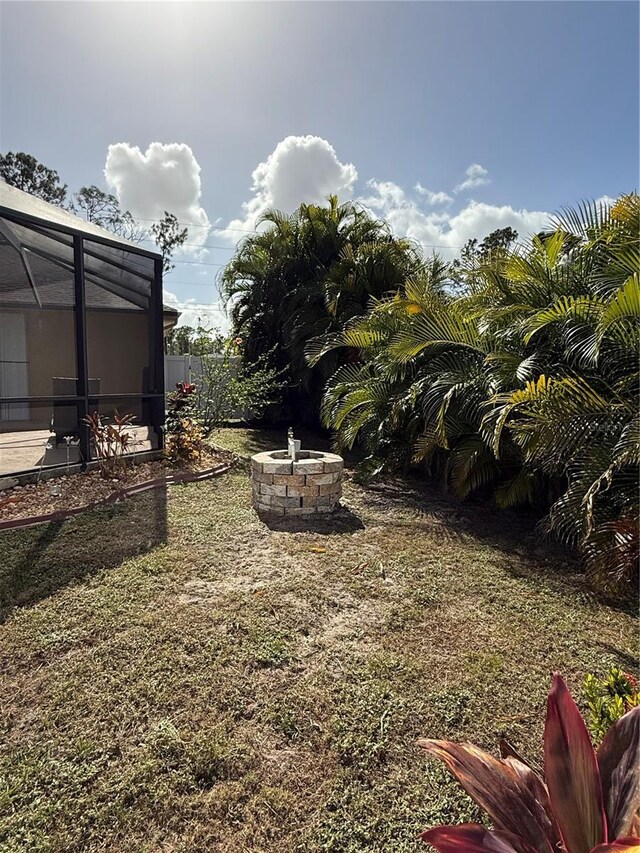 view of yard with glass enclosure and an outdoor fire pit