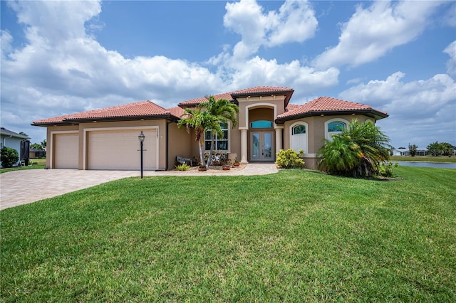 mediterranean / spanish house with a garage, a front yard, and french doors