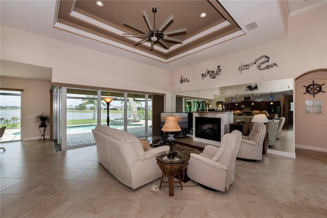 living room featuring ceiling fan, a high ceiling, and a tray ceiling