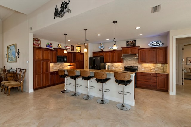 kitchen featuring a kitchen breakfast bar, tasteful backsplash, a kitchen island with sink, and black appliances