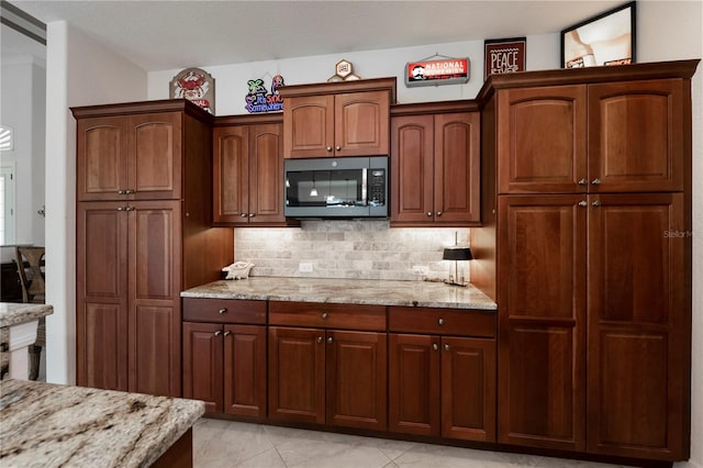 kitchen with decorative backsplash, light tile patterned floors, light stone countertops, and a textured ceiling