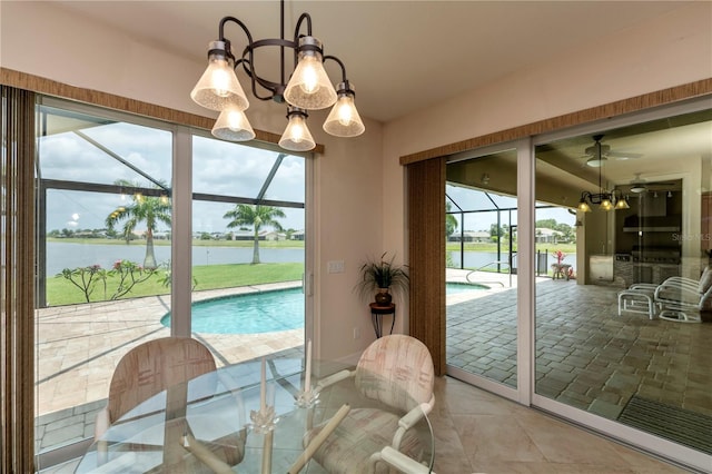 tiled dining room featuring plenty of natural light, a water view, and ceiling fan with notable chandelier