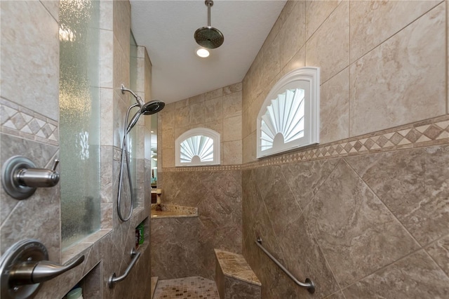 bathroom with a tile shower and tile walls