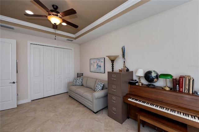 living area featuring ceiling fan, crown molding, and a tray ceiling