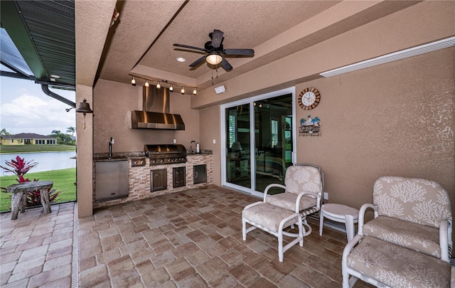 view of patio featuring grilling area, an outdoor kitchen, a water view, sink, and ceiling fan