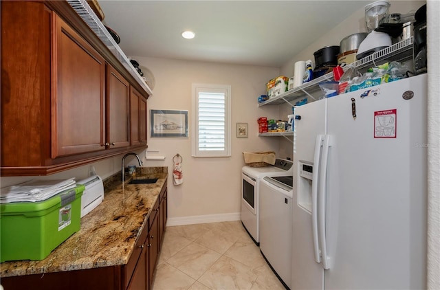 kitchen with light stone countertops, washer and clothes dryer, white fridge with ice dispenser, and sink