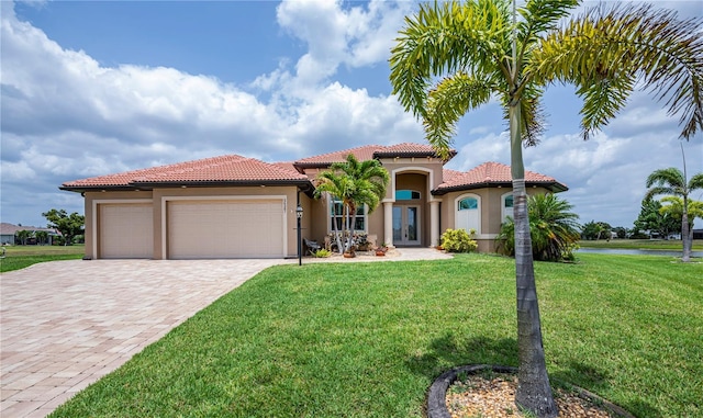 mediterranean / spanish-style home featuring a water view, a garage, and a front lawn