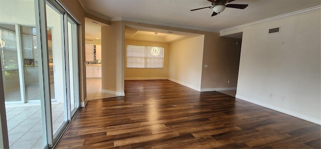 empty room with plenty of natural light, dark hardwood / wood-style flooring, ornamental molding, and ceiling fan with notable chandelier