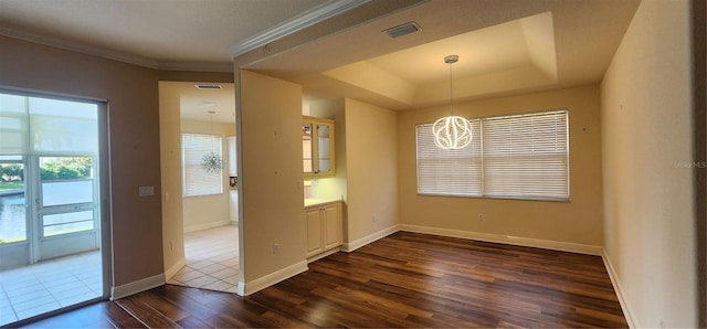 unfurnished dining area featuring a raised ceiling, a chandelier, and dark hardwood / wood-style floors