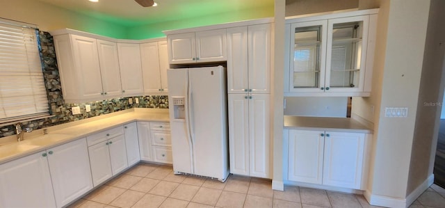 kitchen with white cabinets, white refrigerator with ice dispenser, sink, and light tile patterned floors