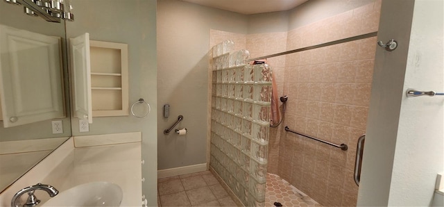 bathroom featuring tile patterned flooring, a tile shower, and sink