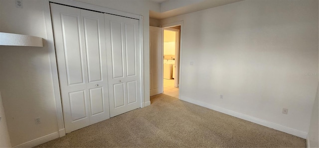 unfurnished bedroom with light colored carpet and a closet