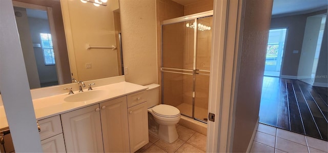 bathroom featuring hardwood / wood-style flooring, a healthy amount of sunlight, toilet, and a shower with door