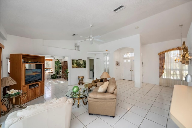 tiled living room featuring ceiling fan with notable chandelier and lofted ceiling