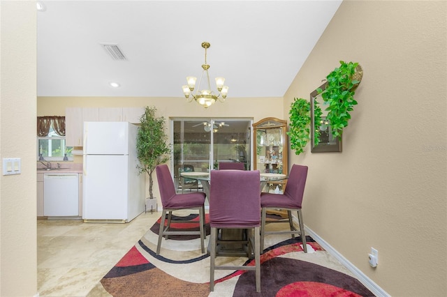 dining area featuring lofted ceiling, sink, and an inviting chandelier