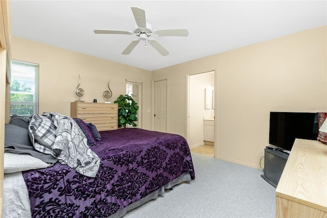 bedroom featuring ceiling fan, light colored carpet, ensuite bathroom, and a closet