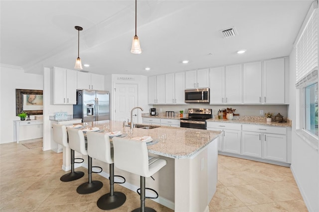 kitchen with white cabinets, appliances with stainless steel finishes, an island with sink, and sink