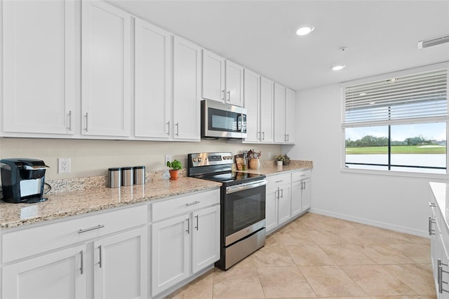 kitchen featuring light stone counters, white cabinets, light tile patterned floors, and appliances with stainless steel finishes