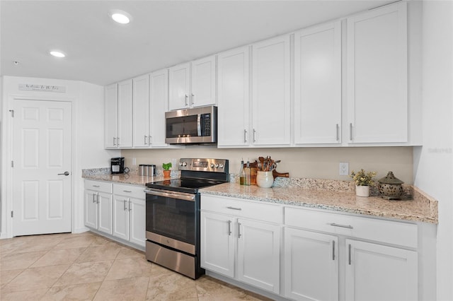 kitchen featuring white cabinetry, light tile patterned flooring, light stone counters, and appliances with stainless steel finishes