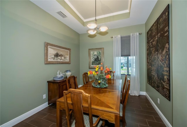 dining room featuring a notable chandelier, a raised ceiling, and crown molding